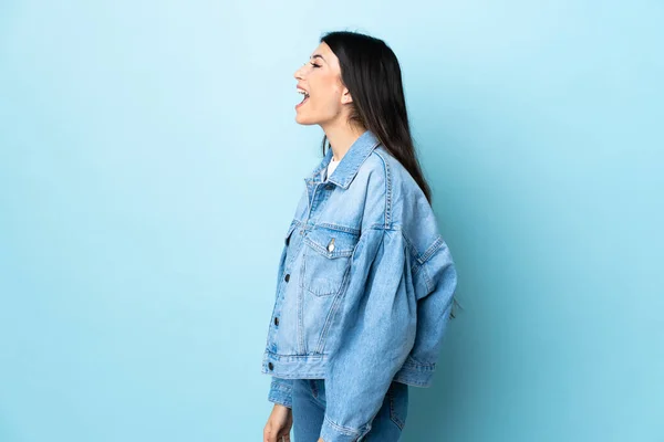 Junges Brünettes Mädchen Auf Isoliertem Blauen Hintergrund Lacht Seitlicher Position — Stockfoto