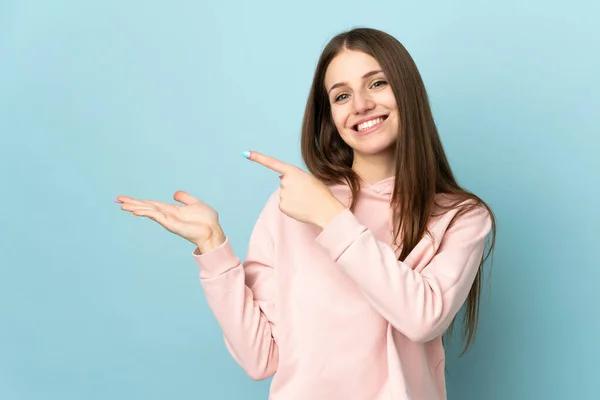 Joven Mujer Caucásica Aislada Sobre Fondo Azul Sosteniendo Espacio Copia —  Fotos de Stock