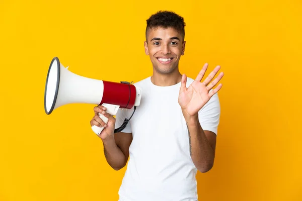 Jovem Brasileiro Isolado Fundo Amarelo Segurando Megafone Saudando Com Mão — Fotografia de Stock