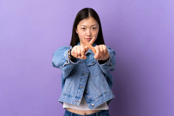 一个年轻的中国姑娘用她的手在紫色背景上做了一个停止动作的手势 — 图库照片