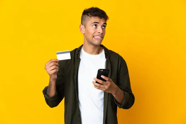 Mladý Brazilský Muž Izolované Žlutém Pozadí Nákup Mobilem Kreditní Kartou — Stock fotografie