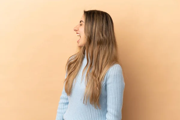 Mujer Joven Caucásica Aislada Sobre Fondo Beige Riendo Posición Lateral —  Fotos de Stock