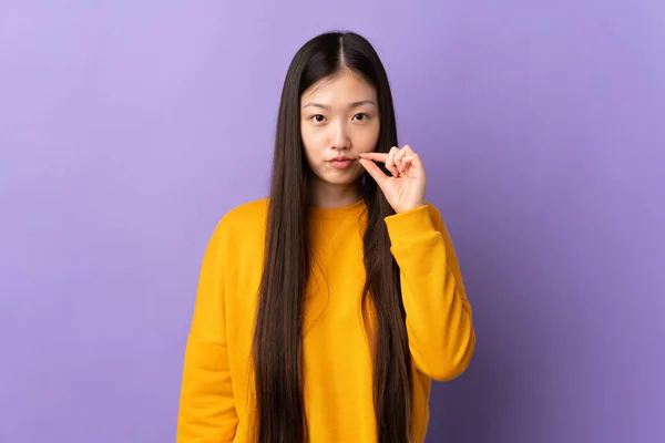 年轻的中国女孩在孤立的紫色背景上表现出沉默的姿态 — 图库照片