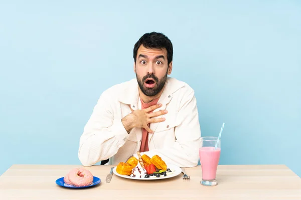 Mężczyzna Przy Stole Jedzący Śniadaniowe Gofry Shake Zaskoczony Zszokowany Patrząc — Zdjęcie stockowe