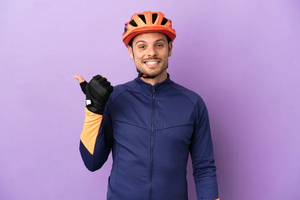 Joven Ciclista Brasileño Aislado Sobre Fondo Púrpura Apuntando Hacia Lado — Foto de Stock