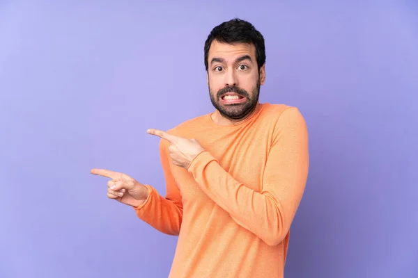 Caucasiano Bonito Homem Sobre Isolado Roxo Fundo Assustado Apontando Para — Fotografia de Stock