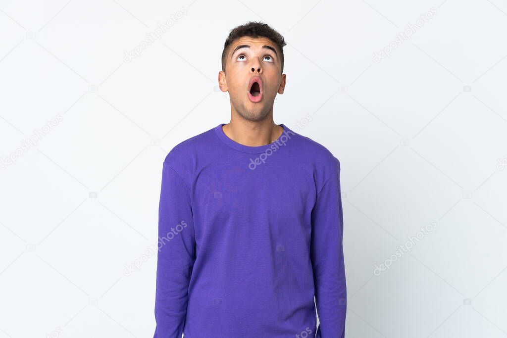 Young brazilian man isolated on white background looking up and with surprised expression