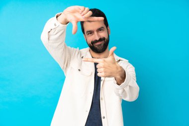 İzole edilmiş mavi arka planda odaklanan beyaz kadife ceketli genç yakışıklı adam. Çerçeve sembolü