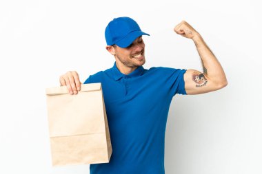 Brezilyalı beyaz arka planda izole edilmiş bir paket yiyecek alıyor. Güçlü bir jest yapıyor.