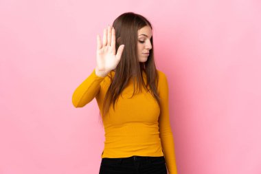 Pembe arka planda izole edilmiş genç beyaz kadın dur hareketi yapıyor ve hayal kırıklığına uğruyor.