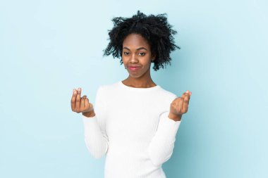 Genç Afrikalı Amerikalı kadın mavi arka planda izole edilmiş para hareketi yapıyor.