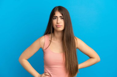 Kafkasyalı genç bir kadın mavi arka planda izole edilmiş, kızgın.