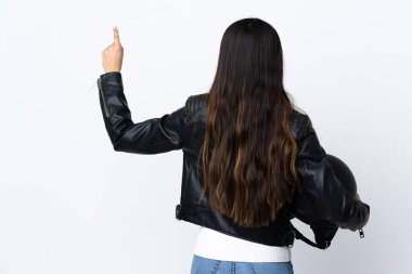 İzole edilmiş beyaz arka planda motosiklet kaskı tutan genç bir kadın işaret parmağıyla işaret ediyor.
