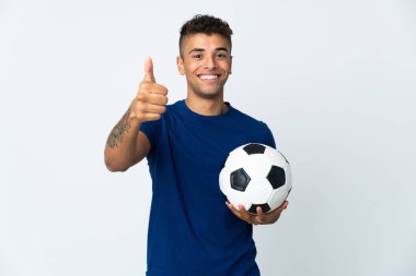 Genç Brezilyalı izole edilmiş arka planda futbol topuyla ve başparmağıyla