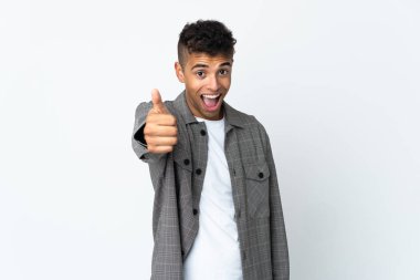 Genç Brezilyalı adam beyaz arka planda izole edildi. Başparmakları havada çünkü iyi bir şey oldu.