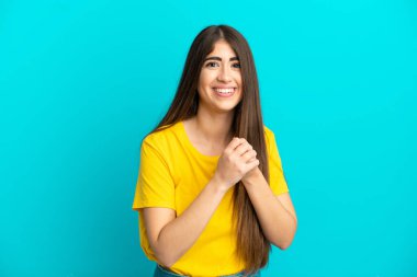 Mavi arka planda izole edilmiş genç beyaz kadın gülüyor.