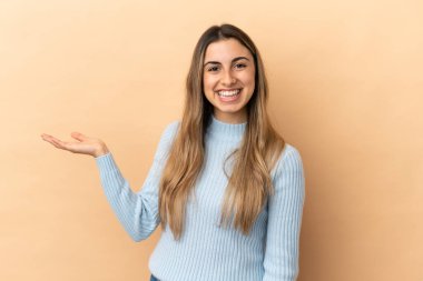 Beyaz tenli genç bir kadın, bej arka planda izole edilmiş. Elinde bir ilan vermek için avuç içi hayali fotokopi makinesi var.
