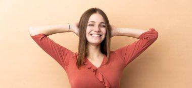 Bej arka planda izole edilmiş genç beyaz kadın gülüyor.