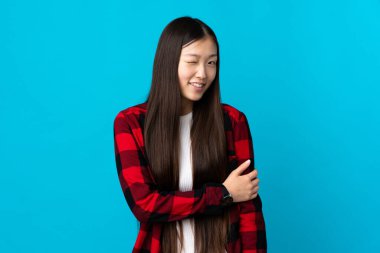 Genç Çinli kız mavi arka planda gülüyor.