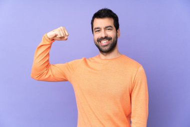 Kafkasyalı yakışıklı adam, izole edilmiş mor arka planda güçlü bir hareket yapıyor.