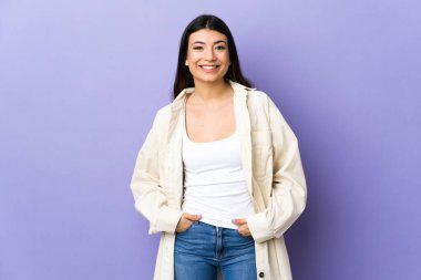 Genç esmer kadın, izole edilmiş mor arka planda gülüyor.