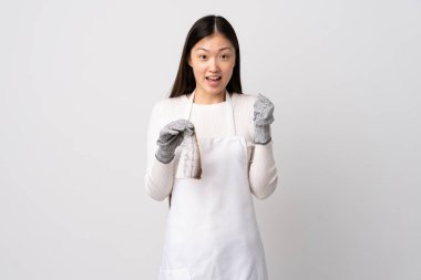 Çinli balıkçı önlük takıyor ve bir çiğ balığı izole edilmiş beyaz arka planda tutarak galibiyeti kutluyor.