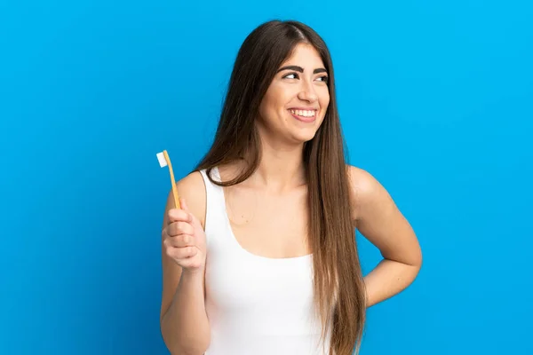 Młody Biały Kobieta Mycie Zęby Odizolowany Niebieski Tło Patrząc Boku — Zdjęcie stockowe
