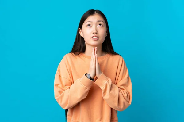 Ung Kinesisk Flicka Över Isolerad Blå Bakgrund Håller Handflatan Samman — Stockfoto