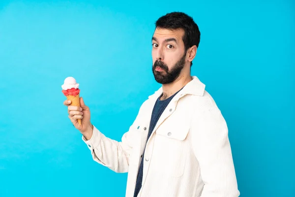 一个年轻男子 带着玉米粒冰淇淋 背景是孤立的蓝色 — 图库照片