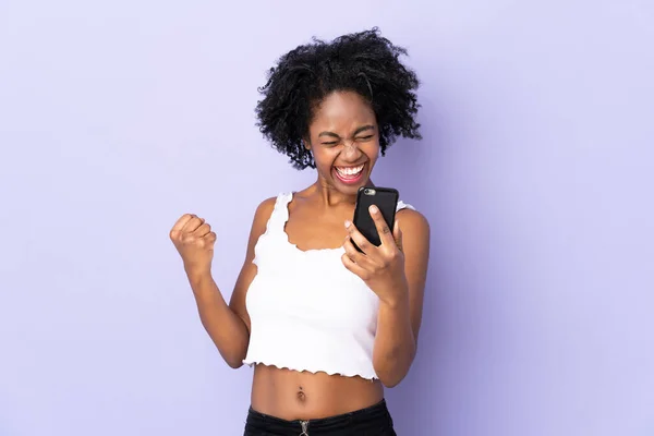 Ung Afroamerikansk Kvinna Isolerad Lila Bakgrund Med Telefon Seger Position — Stockfoto