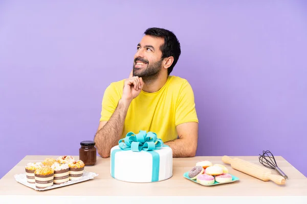 Mann Einem Tisch Mit Einem Großen Kuchen Denkt Eine Idee — Stockfoto