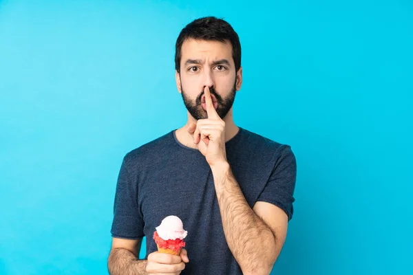 年轻男子在孤立的蓝色背景上戴着软木塞冰淇淋 露出沉默的姿态 用手指捂住嘴 — 图库照片