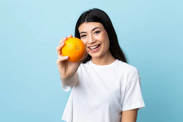 Ung Brunett Flicka Över Isolerad Blå Bakgrund Håller Orange — Stockfoto