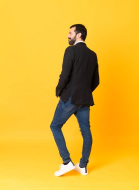 İzole edilmiş sarı arka planda tam boy iş adamı görüntüsü.