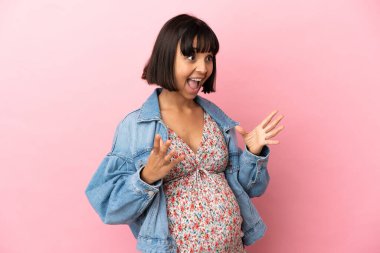 Yüzünde sürpriz bir ifade olan, pembe bir geçmişi olan hamile bir kadın.