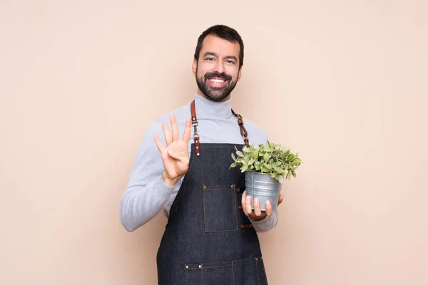 Homem Segurando Uma Planta Sobre Fundo Isolado Feliz Contando Quatro — Fotografia de Stock