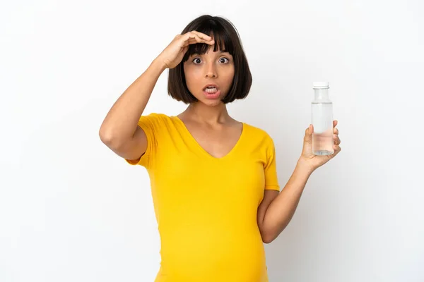 白い背景に孤立した水のボトルを持っている若い妊婦は横を見ながら驚きのジェスチャーを行います — ストック写真