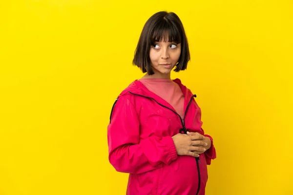 Mujer Embarazada Joven Sobre Fondo Amarillo Aislado Que Tiene Dudas — Foto de Stock