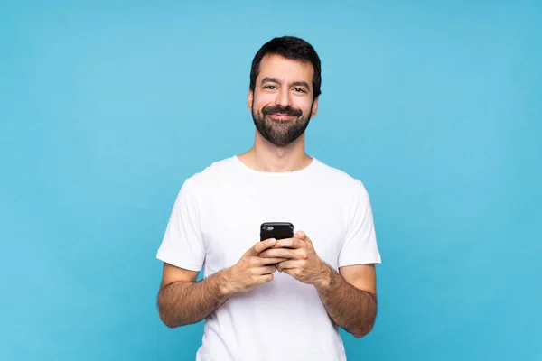 Mavi Arka Planda Sakallı Genç Bir Adam Cep Telefonuyla Mesaj — Stok fotoğraf