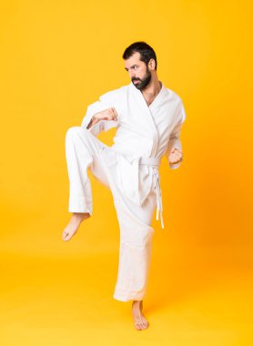 İzole edilmiş sarı arka planda karate yapan bir adamın tam boy fotoğrafı.
