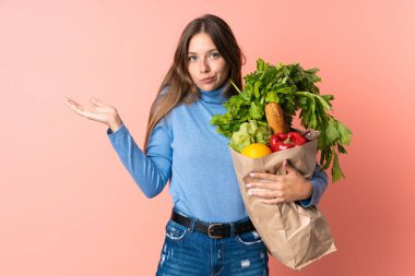 Genç Litvanyalı bir kadın alışveriş torbası tutuyor. El kaldırırken şüpheleri var.