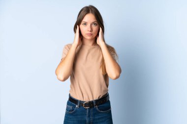 Genç Litvanyalı kadın mavi arka planda izole edilmiş hayal kırıklığına uğramış ve kulaklarını kapatmış