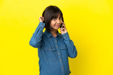 Sarı arka planda izole edilmiş cep telefonu kullanan hamile kadının şüpheleri var.