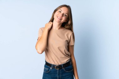 Genç Litvanyalı kadın mavi arka planda izole edilmiş gülüyor.