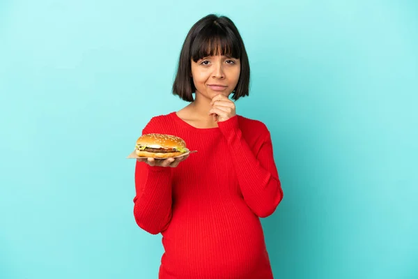 Young Pregnant Woman Holding Burger Isolated Background Thinking — Stock Photo, Image