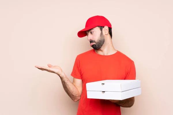 Mladý Muž Drží Pizzu Nad Izolovaným Pozadím Drží Copyspace Pochybnostmi — Stock fotografie