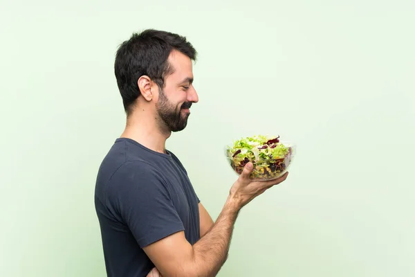 年轻英俊的男人 在孤立的绿墙上放沙拉 — 图库照片