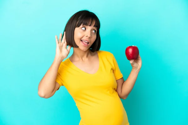 Schwangere Hält Einen Apfel Isoliert Auf Blauem Hintergrund Und Hört — Stockfoto