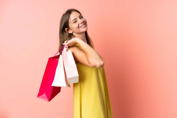 若いリトアニアの女性はピンクの背景に隔離されたショッピングバッグや笑顔を保持 — ストック写真