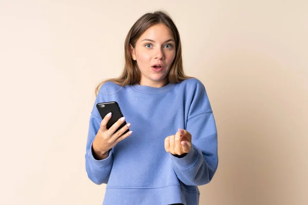 Mladý Litevský Žena Pomocí Mobilního Telefonu Izolované Béžové Pozadí Překvapený — Stock fotografie